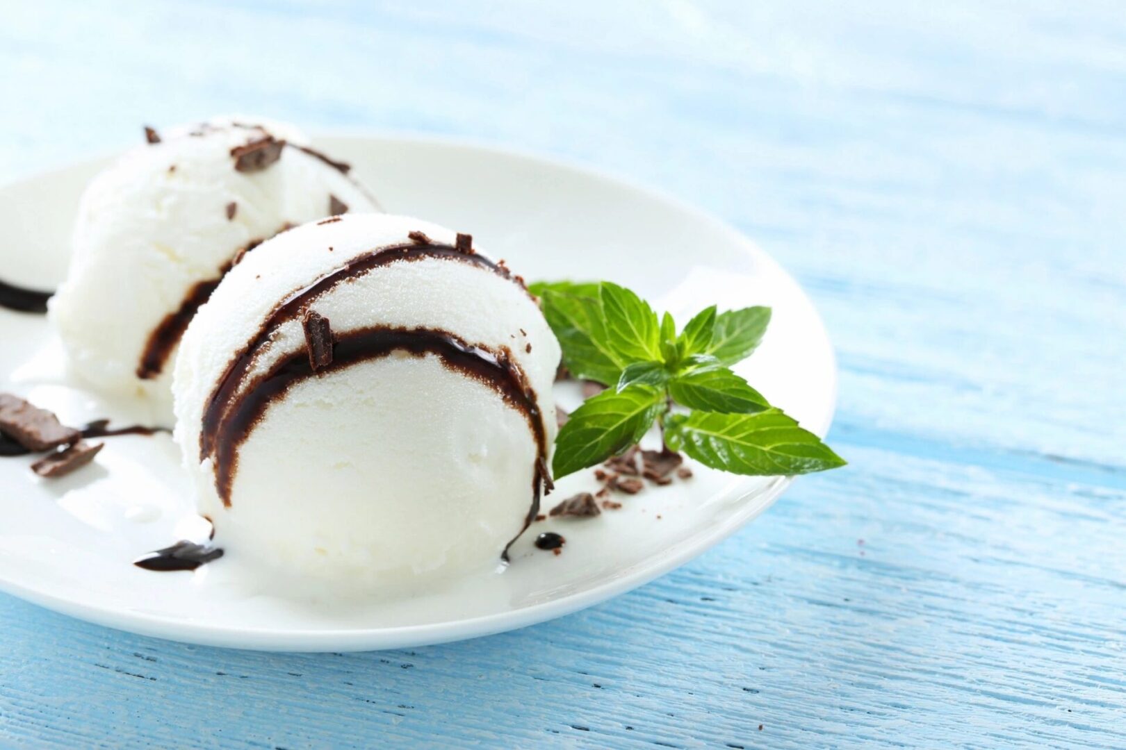 A white plate topped with ice cream and chocolate.