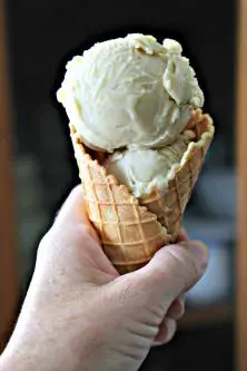 A person holding an ice cream cone in their hand.